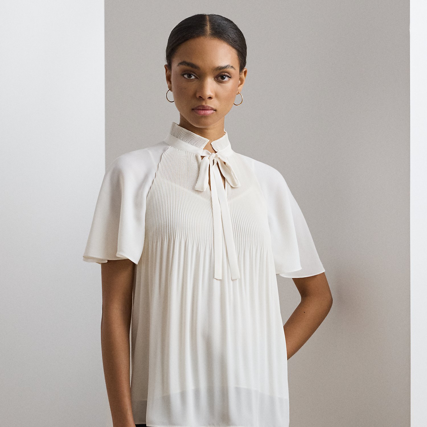 Cut for a breezy, relaxed silhouette, this blouse is defined by flutter sleeves and delicate sunray pleating. Crafted with semi-sheer georgette, it comes with a camisole lining for opacity.