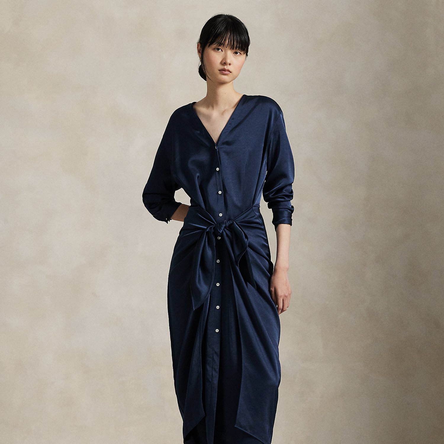 Rendered in soft-falling, lightweight satin, this elegant piece merges classic shirtdress details, like a buttoned placket and pleated back yoke, with a V-neckline and tie-front wrap detail at the waist.