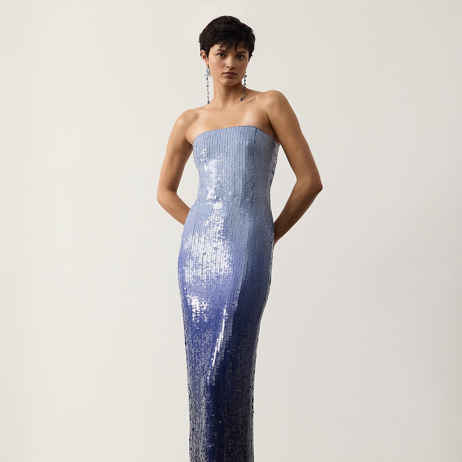 The Jennette dress reflects the serene beauty found in the interplay of sea and sky with its striking ombré colouring. To begin, a team of five specialised technicians applied 220,000 square-shaped sequins across a cornflower blue silk georgette base, resulting in an allover lacquered finish. Once applied, the sequins are specially dyed by hand to achieve a stunning dégradé effect. This dress is designed with a strapless column silhouette, creating an elegant style that transcends time.