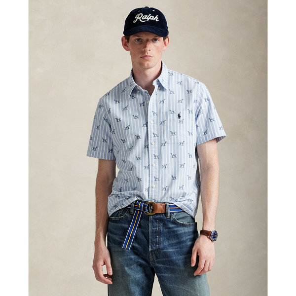 The Oxford shirt made its debut very early in  Ralph Lauren Lauren’s designs, and since then, it has solidified its status as a pillar of the Polo look. Our fabric is developed with a secret wash, which gives it instant character, ease and a heathered softness – what we refer to as "the perfect rumple". The formula is so unique that it's been kept in a safe for more than three decades. Today, Mr Lauren continues to create countless variations of his iconic shirt, including this short-sleeve version that combines classic stripes with a printed pointer dog motif.